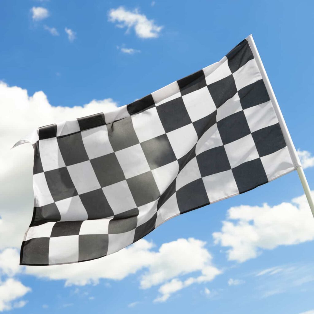 Checkered flag waving in the wind with white clouds on background - 1 to 1 ratio