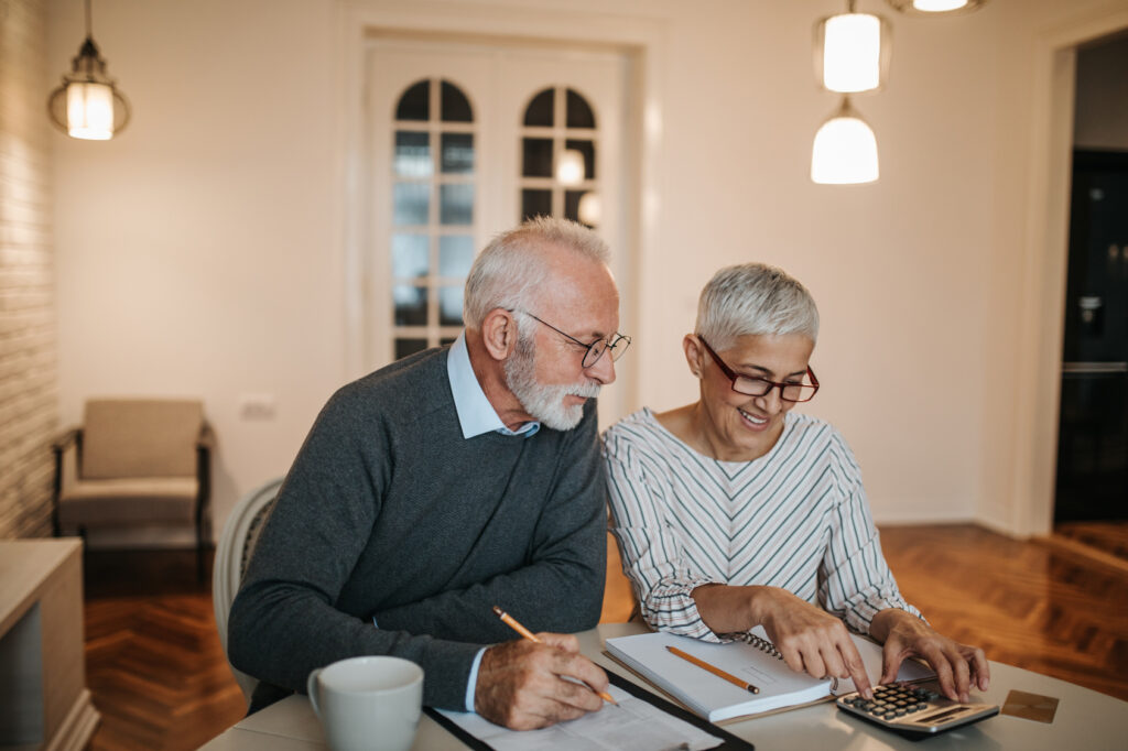 happy retired couple looking over their finances with a calculator